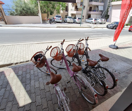 Three bicycles with baskets parked on a sidewalk next to a street.