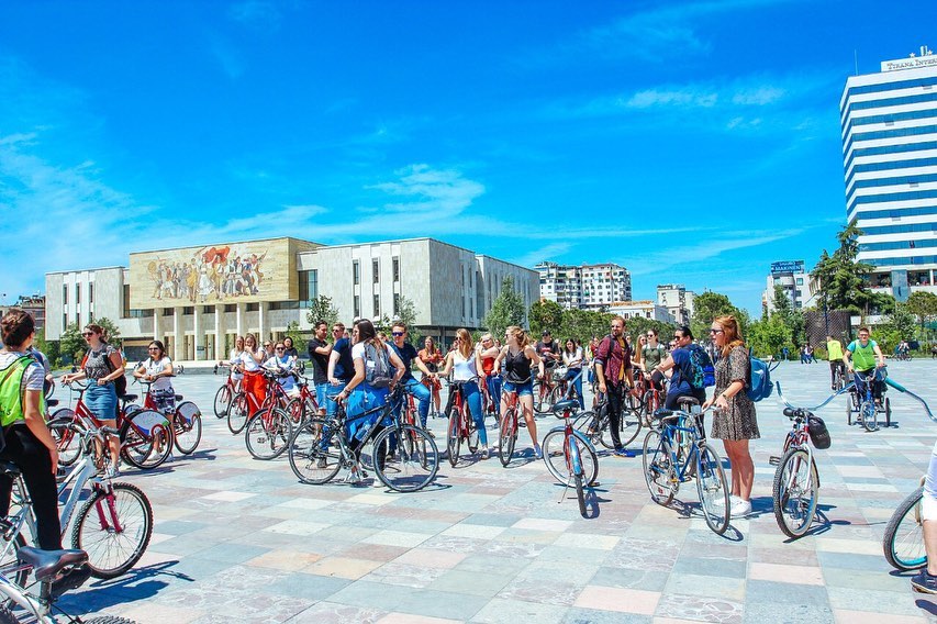 group of tourists cycling the city center of Tirana in Scanderbeg Square for a Guided Bike Tour